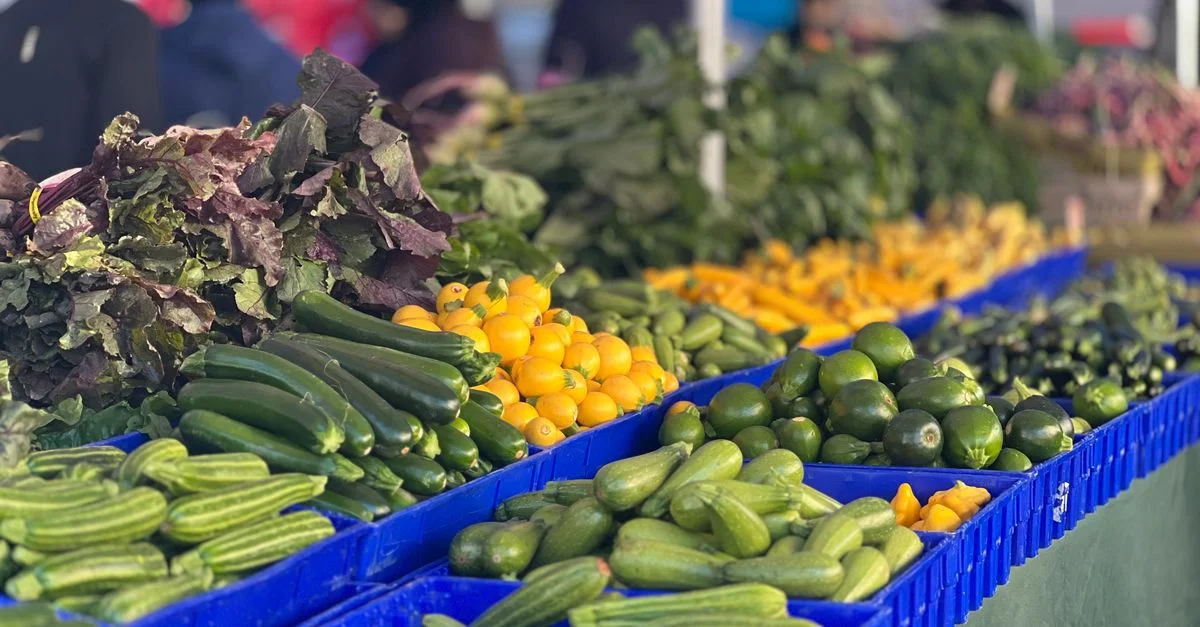 Une variété colorée de légumes frais dans des paniers au marché agricole en plein air.