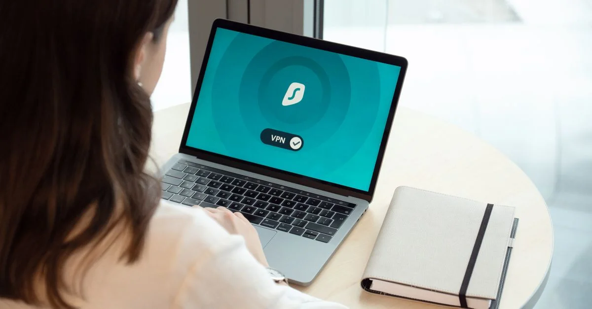 Une femme travaillant sur un ordinateur portable avec une icône VPN à l'écran pour une navigation en ligne sécurisée.